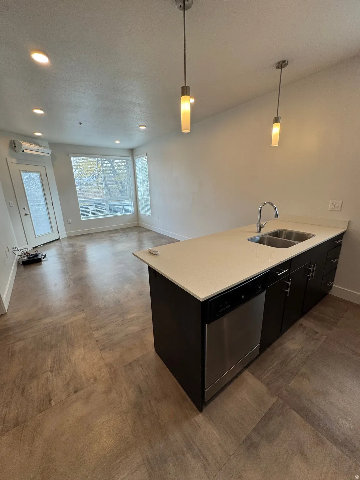 Modern kitchen island featuring a dual-basin stainless steel sink, a stainless steel dishwasher, and a light-toned countertop