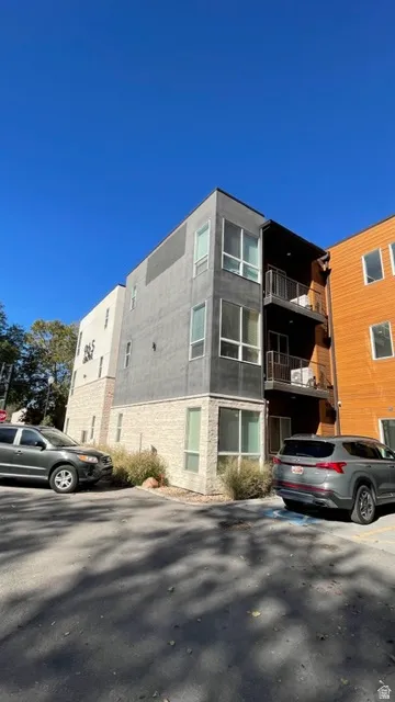 Modern multi-story building featuring a gray stucco facade and light-colored stone accents