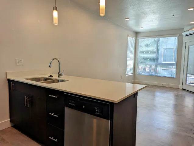 Kitchen island with a double basin sink, chrome faucet, and integrated stainless steel dishwasher
