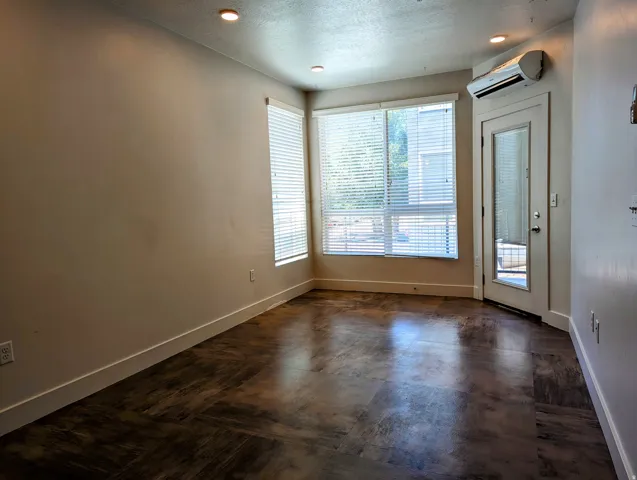 Room featuring wood-finish flooring, recessed lighting, and expansive windows with horizontal blinds