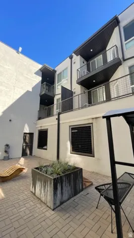 Modern multi-story building featuring white stucco siding and dark-paneled accents