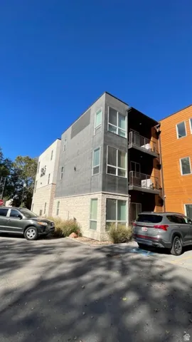 Modern multi-story building featuring a gray stucco facade and light-colored stone accents