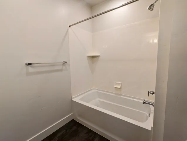 Full bathtub and shower combination with white surround, chrome fixtures, and a wall-mounted towel bar