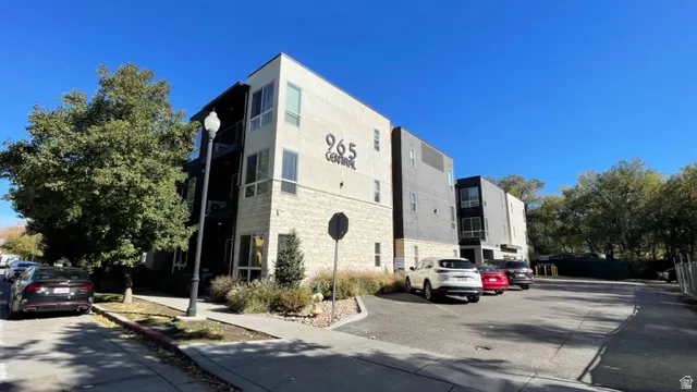 Modern multi-story building featuring a facade of light-colored stone and dark vertical siding