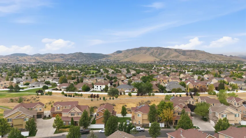Expansive residential neighborhood featuring numerous single-family homes with diverse architectural styles, mature trees, and mountainous terrain in the background