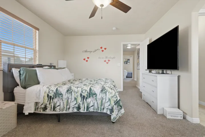 Carpeted bedroom featuring a ceiling fan with integrated lighting, a window with horizontal blinds, and a built-in closet with a white door