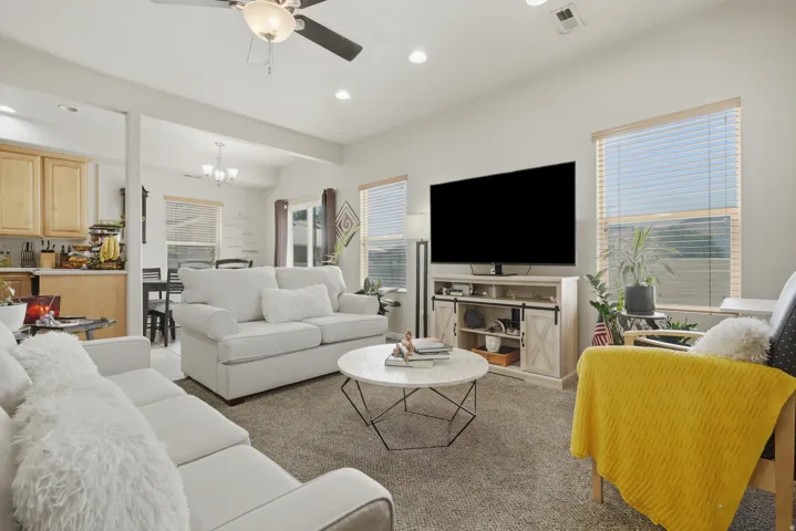 Living area featuring soft gray carpeting, a ceiling fan with integrated lighting, and recessed lighting
