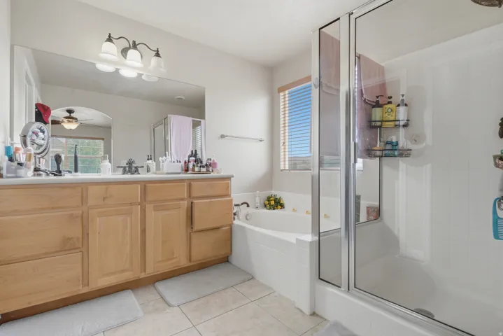 Bathroom featuring a double vanity with wood-finish cabinetry, a framed mirror, and a three-light fixture
