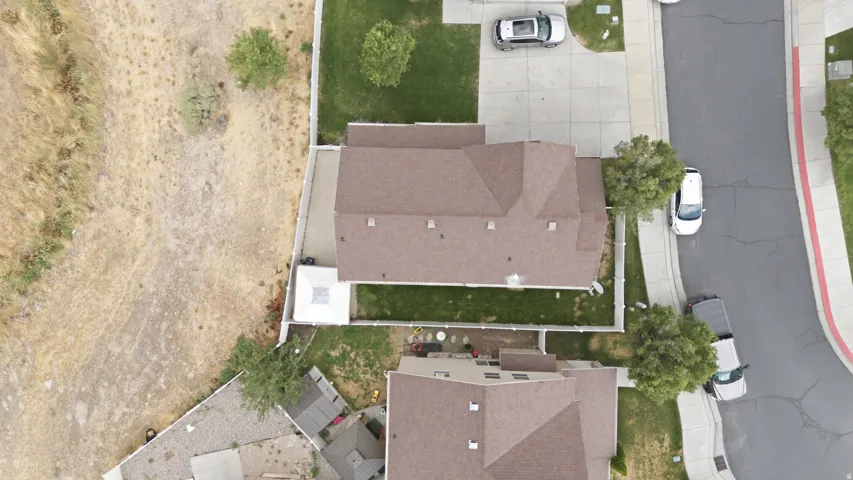 Property featuring a brown shingle roof, a paved driveway, and a fenced backyard with green lawn areas