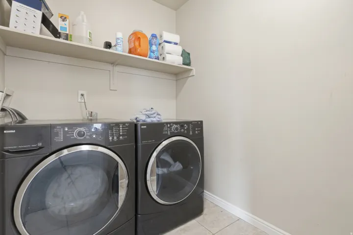 Dedicated laundry area featuring a wall-mounted shelf, light-colored wall paint, and tiled flooring