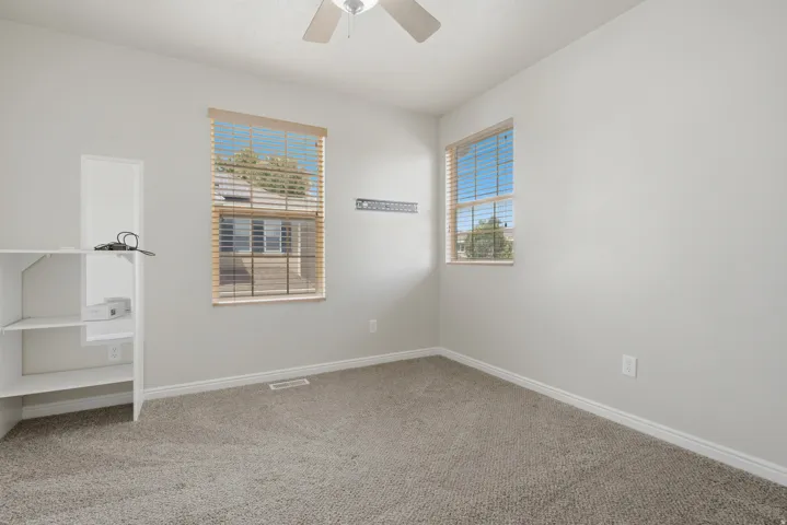 Spacious room featuring neutral carpeting, light-toned walls, and a ceiling fan with integrated lighting