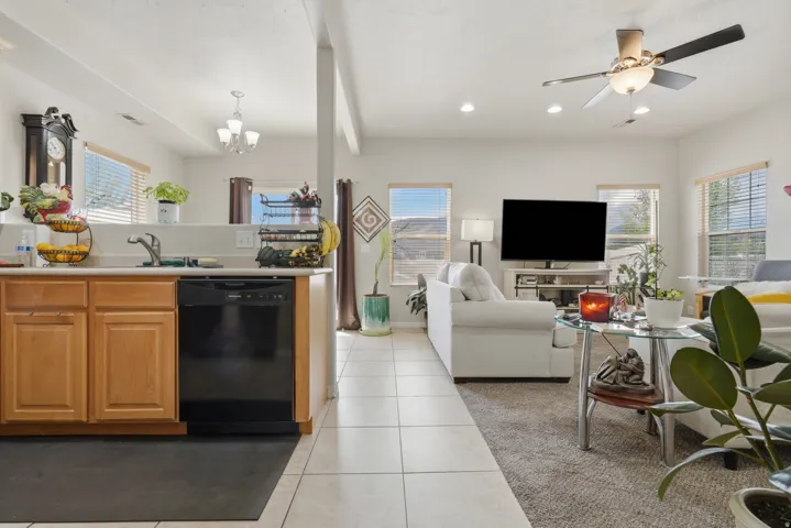 Open concept living space featuring a kitchen with light wood cabinetry and a black dishwasher, and a living area with recessed lighting