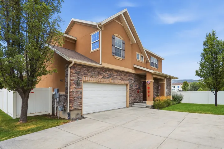 Stucco and stone facade home featuring an attached two-car garage, concrete driveway, and front entry porch with columns