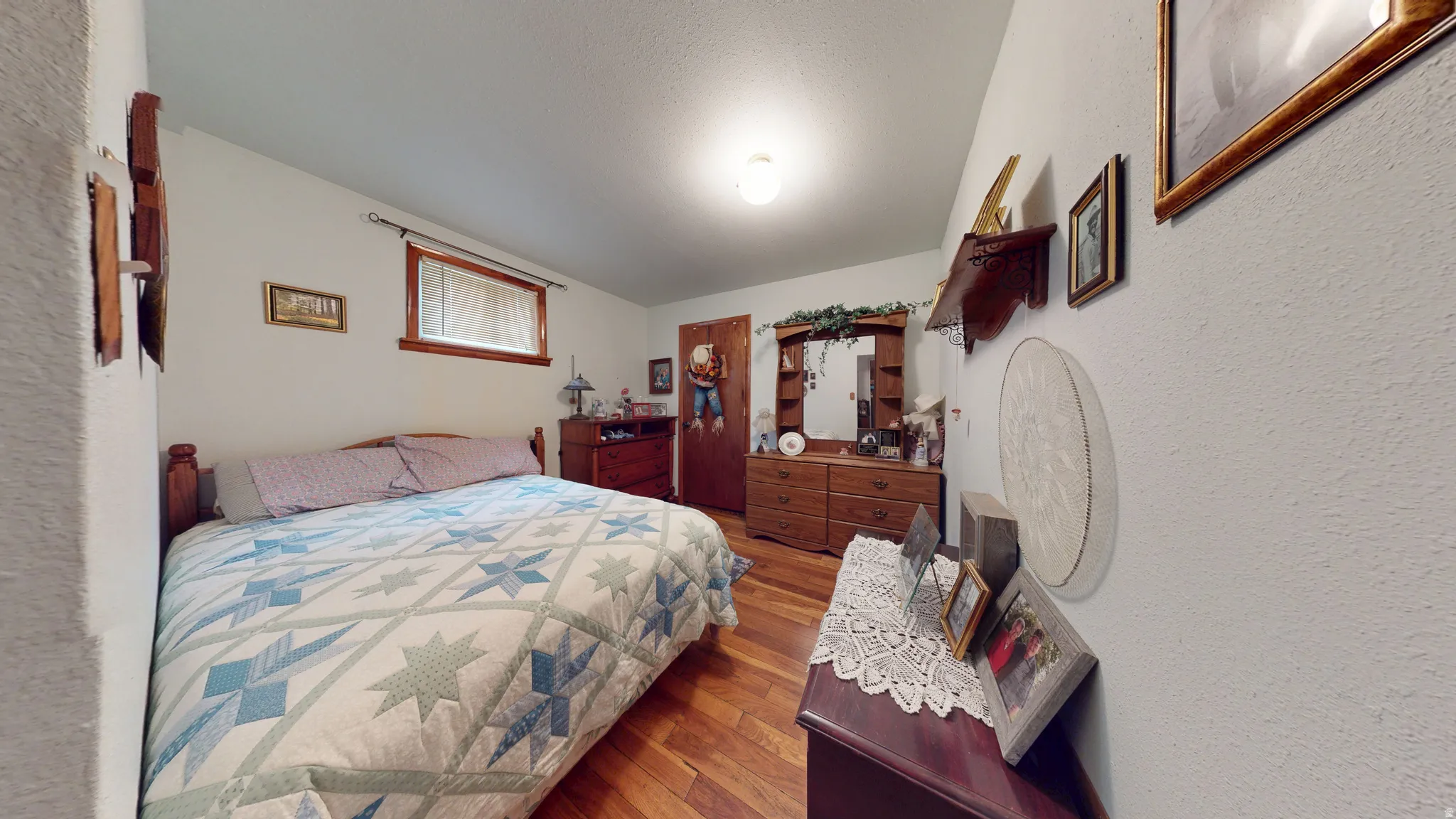 Bedroom featuring wood-finish flooring, a window with wood trim, and a ceiling-mounted light fixture