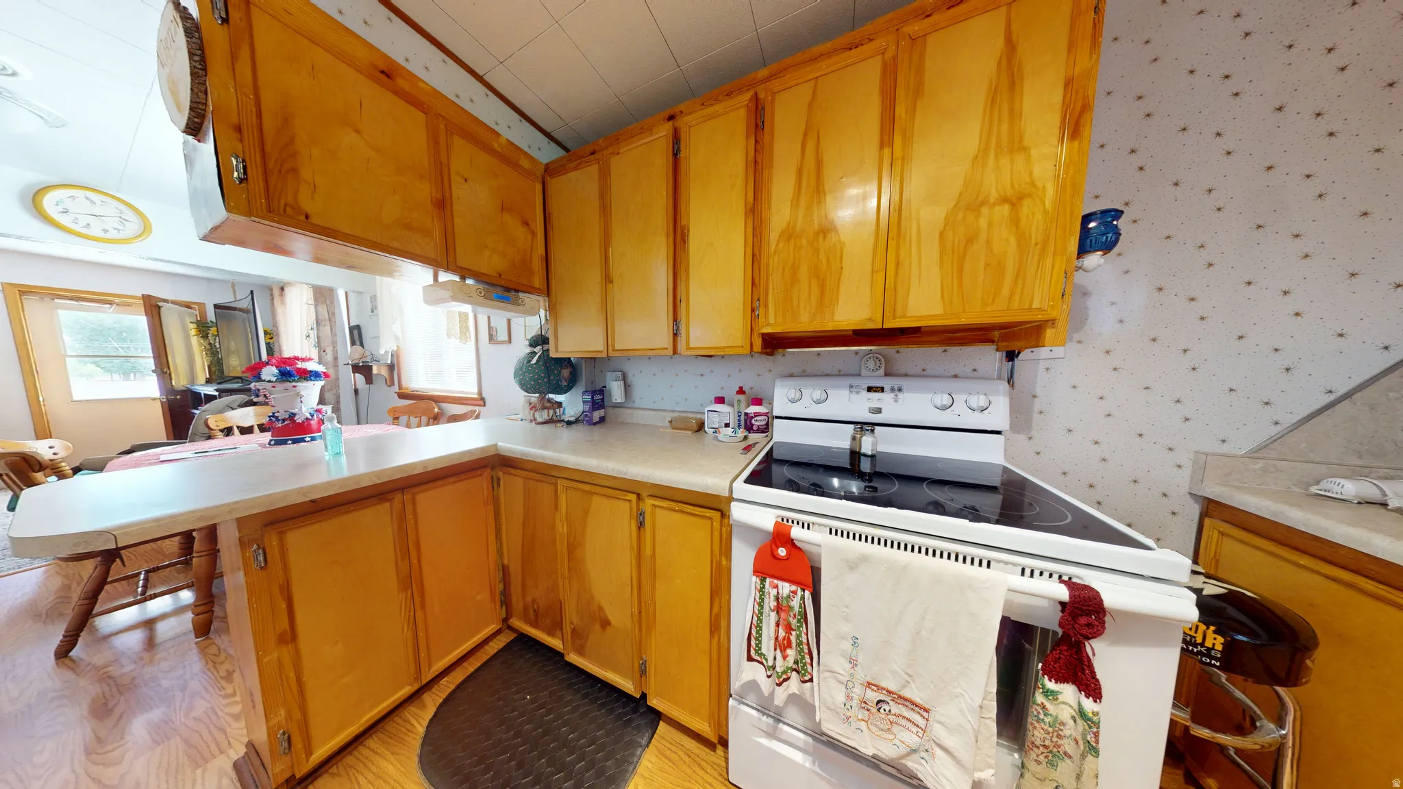 Kitchen featuring wood cabinetry, laminate countertops, a built-in cooktop, and an integrated breakfast bar