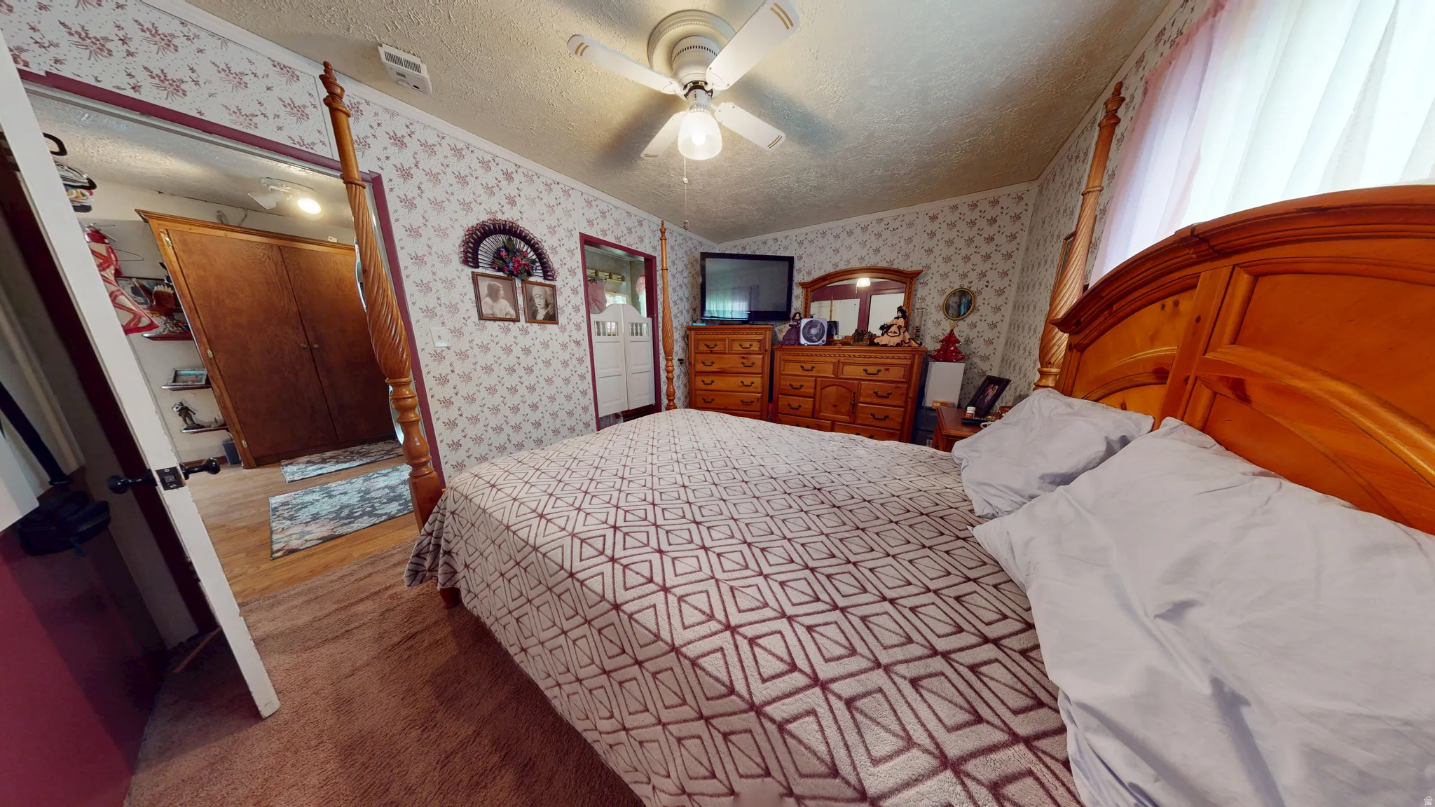 Bedroom featuring textured wallpaper and ceiling fan