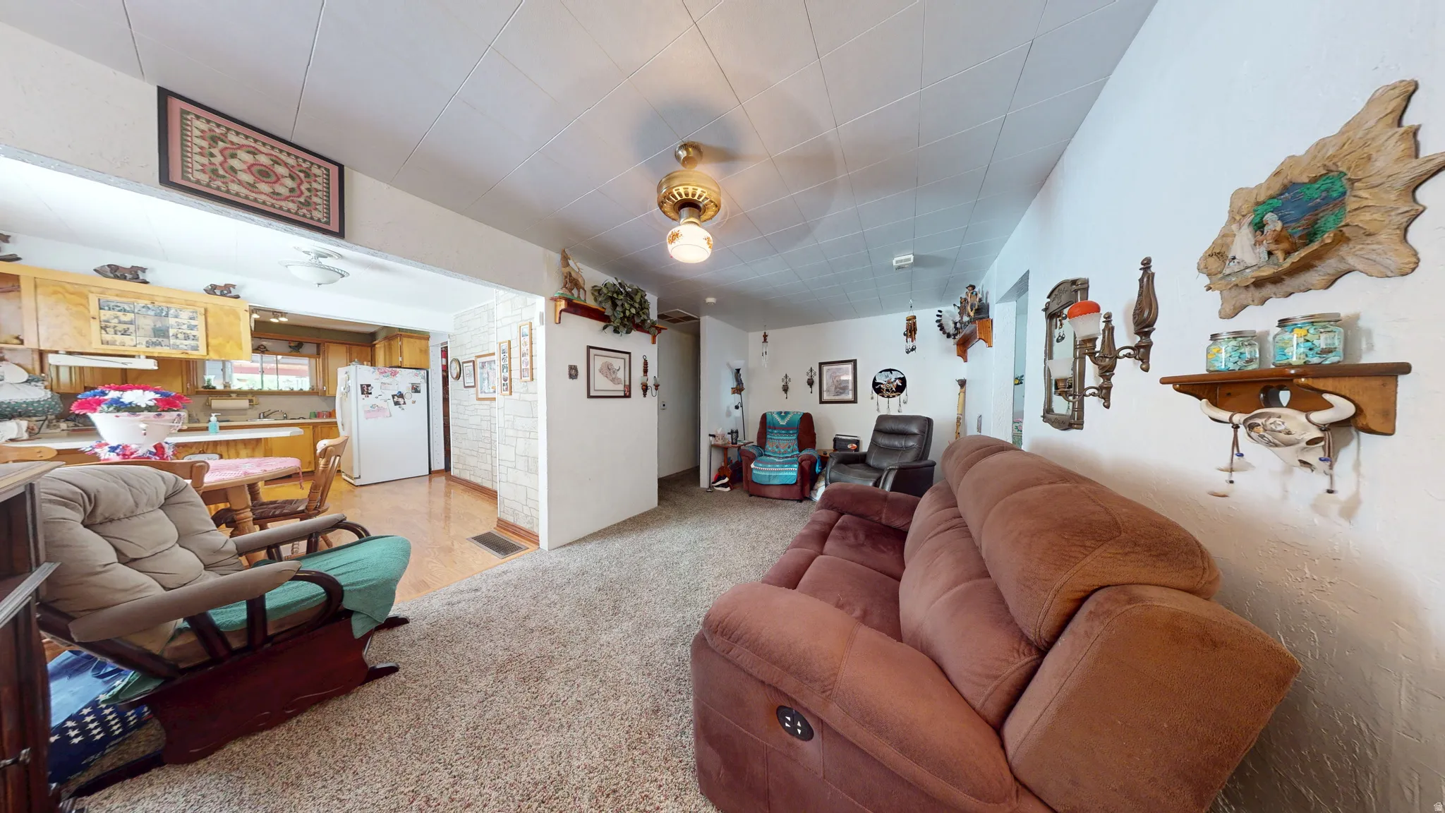 Open-concept living area featuring plush carpet flooring and a ceiling fan