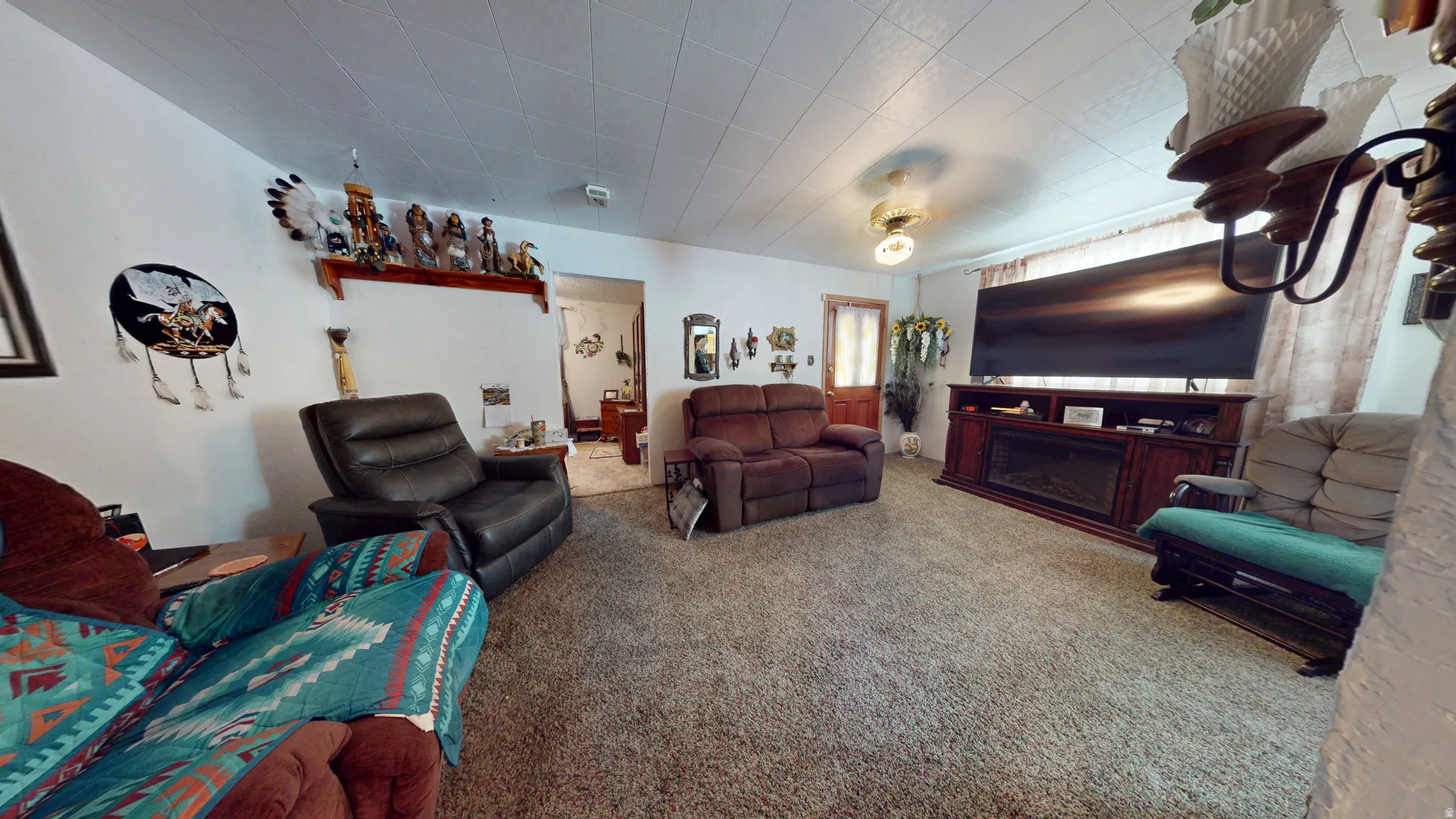 Living area featuring neutral wall tones, textured ceiling, a built-in electric fireplace with media console, and a central ceiling light fixture