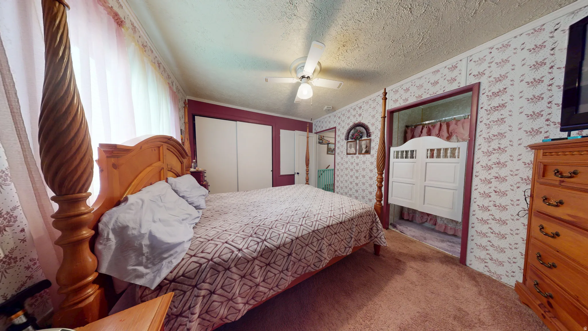 Carpeted room featuring a ceiling fan, wall paneling, and a framed doorway with cafe-style doors
