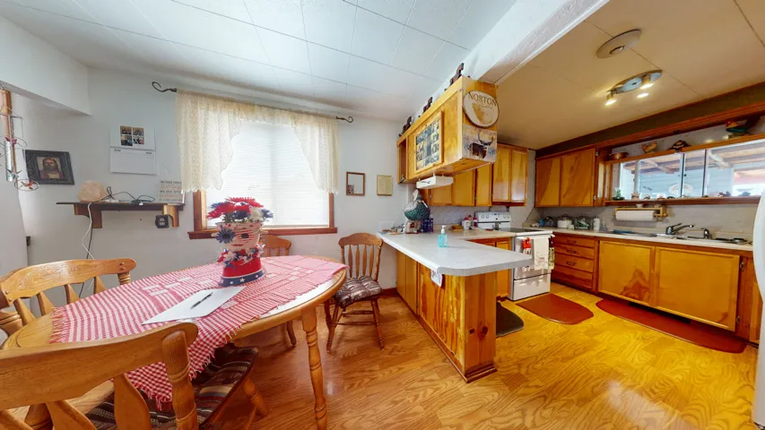 Kitchen featuring wood-finish flooring, light wood cabinetry, a breakfast bar with a solid surface countertop, and recessed lighting