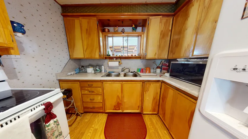 Kitchen featuring wood cabinetry, a double basin sink, a window, wood-finish flooring, and a white oven range