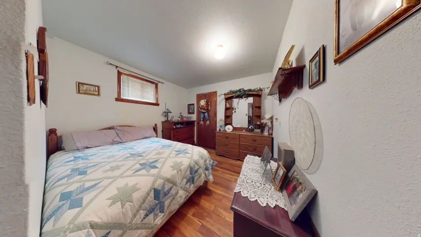 Bedroom featuring wood-finish flooring, a window with wood trim, and a ceiling-mounted light fixture