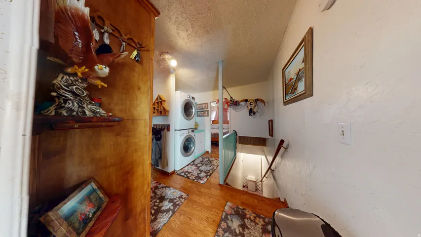 Dedicated laundry area featuring stacked appliances and wood-finish flooring