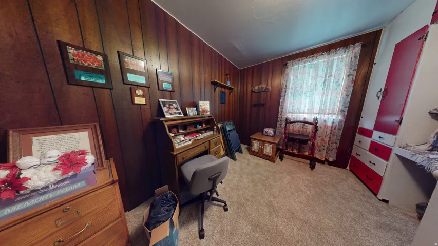 Interior room featuring wood-finish wall paneling, carpeted flooring, and a window with natural light