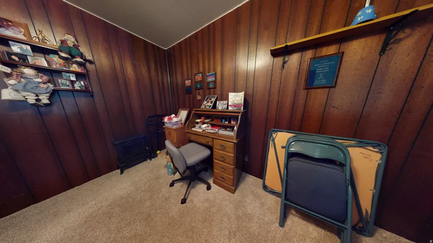 Room featuring wood paneling, wall-mounted shelving, and carpet flooring