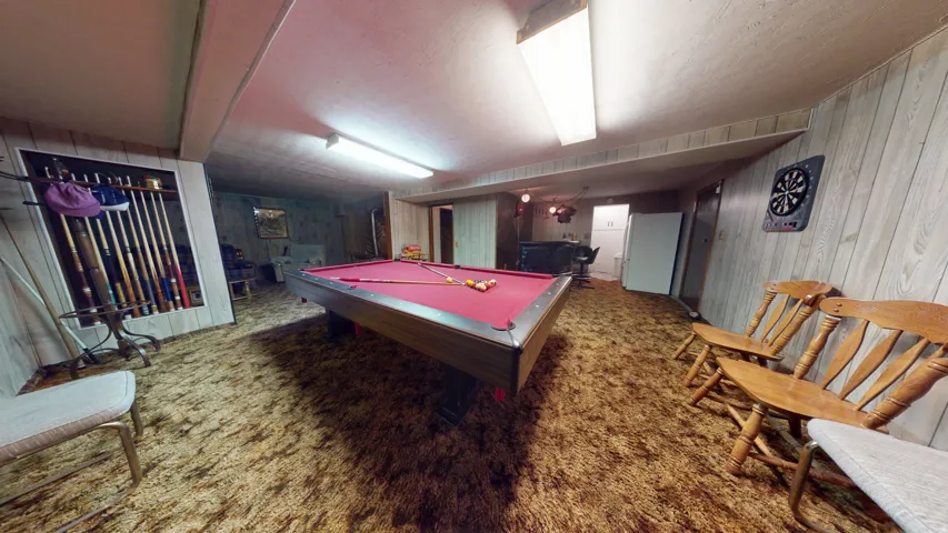 Recreation room featuring a pool table with red felt, wood-paneled walls, and textured carpeting