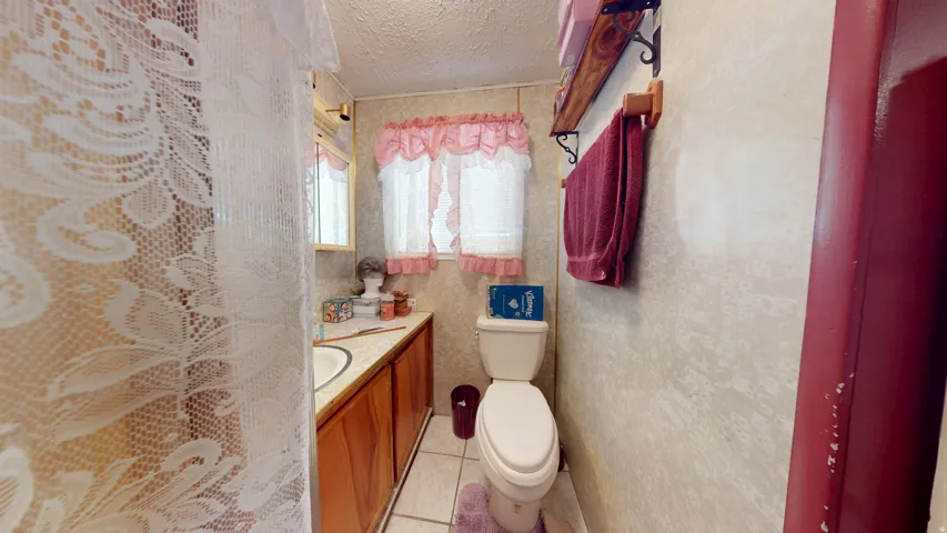 Bathroom featuring a vanity with an integrated sink, a wall-mounted mirror, wood-finish cabinetry, and a toilet
