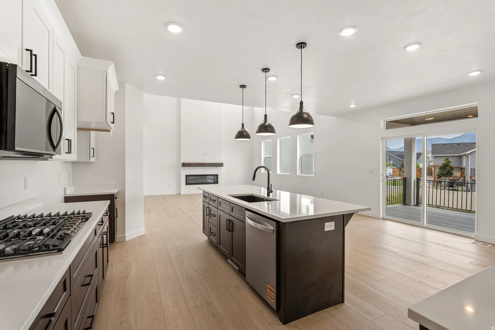 Open-concept living space with light wood-finish flooring, white walls, and recessed lighting