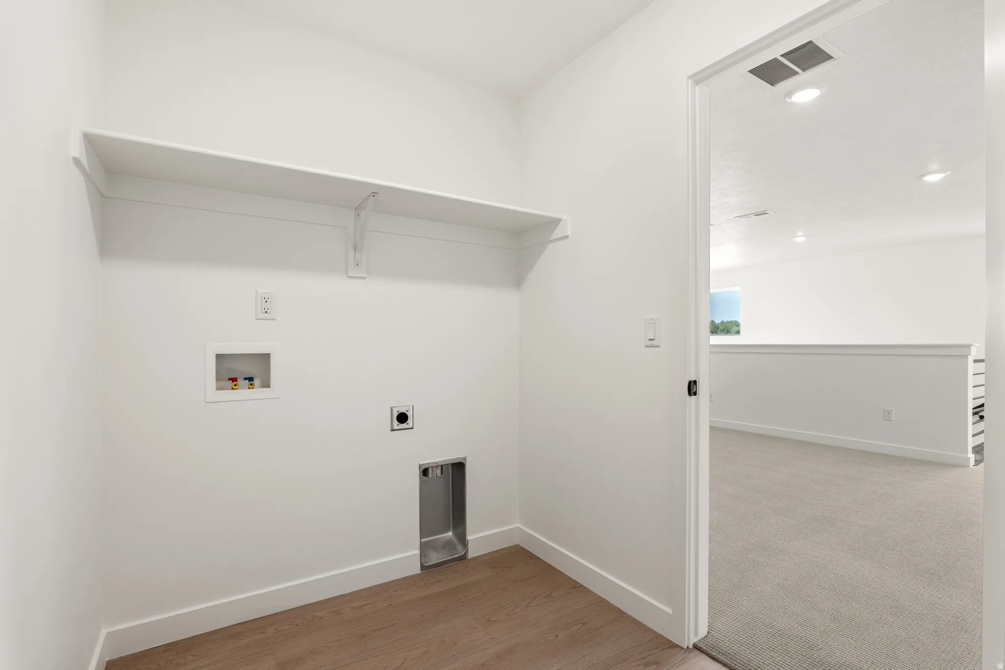 Dedicated laundry area featuring a built-in shelf, plumbing hookups, and wood-finish flooring