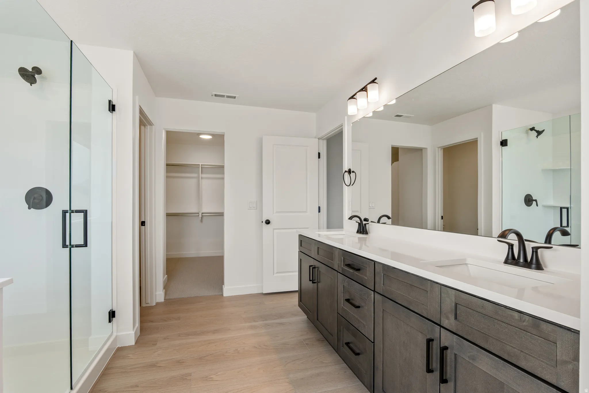 Modern bathroom featuring a double vanity with dark wood-finish cabinetry, white countertops, and matte black fixtures