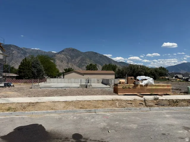Cleared lot featuring a concrete foundation, building materials, and distant mountains