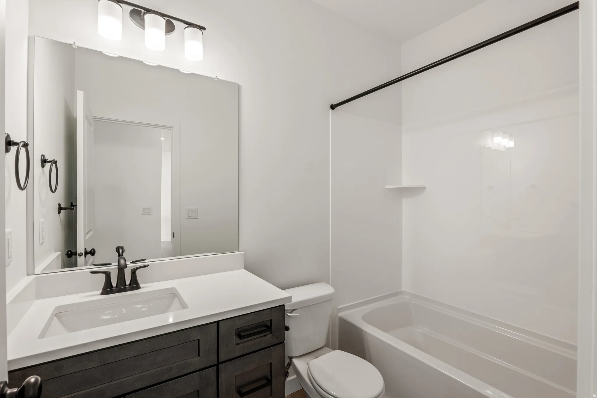 Bathroom featuring a vanity with dark wood-finish cabinetry, a white countertop, and a rectangular undermount sink with a matte black faucet