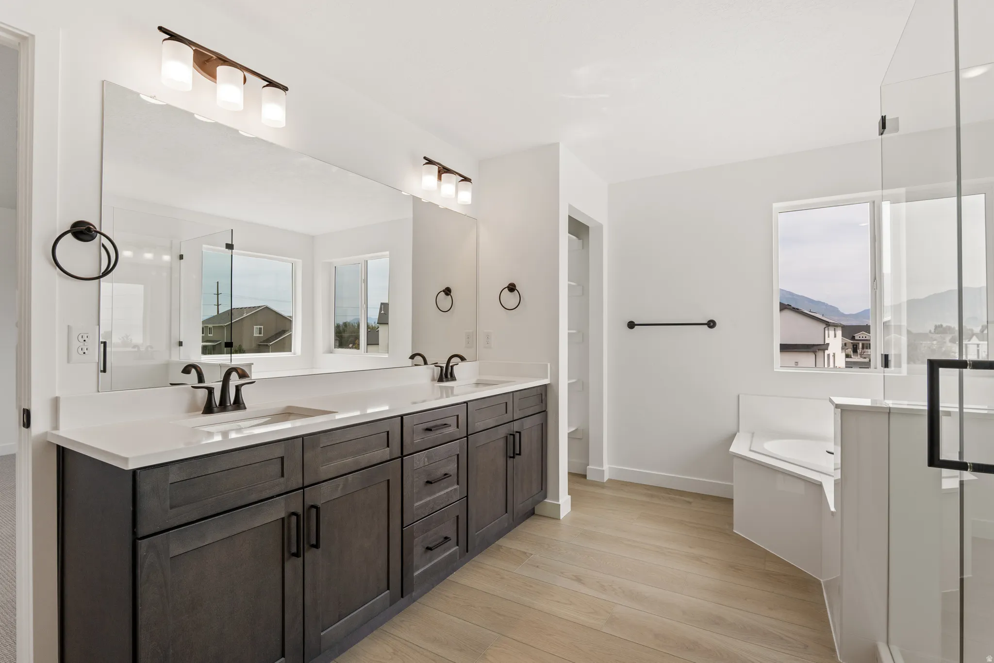 Dual vanity featuring dark wood-finish cabinetry, quartz countertops, and matte black fixtures