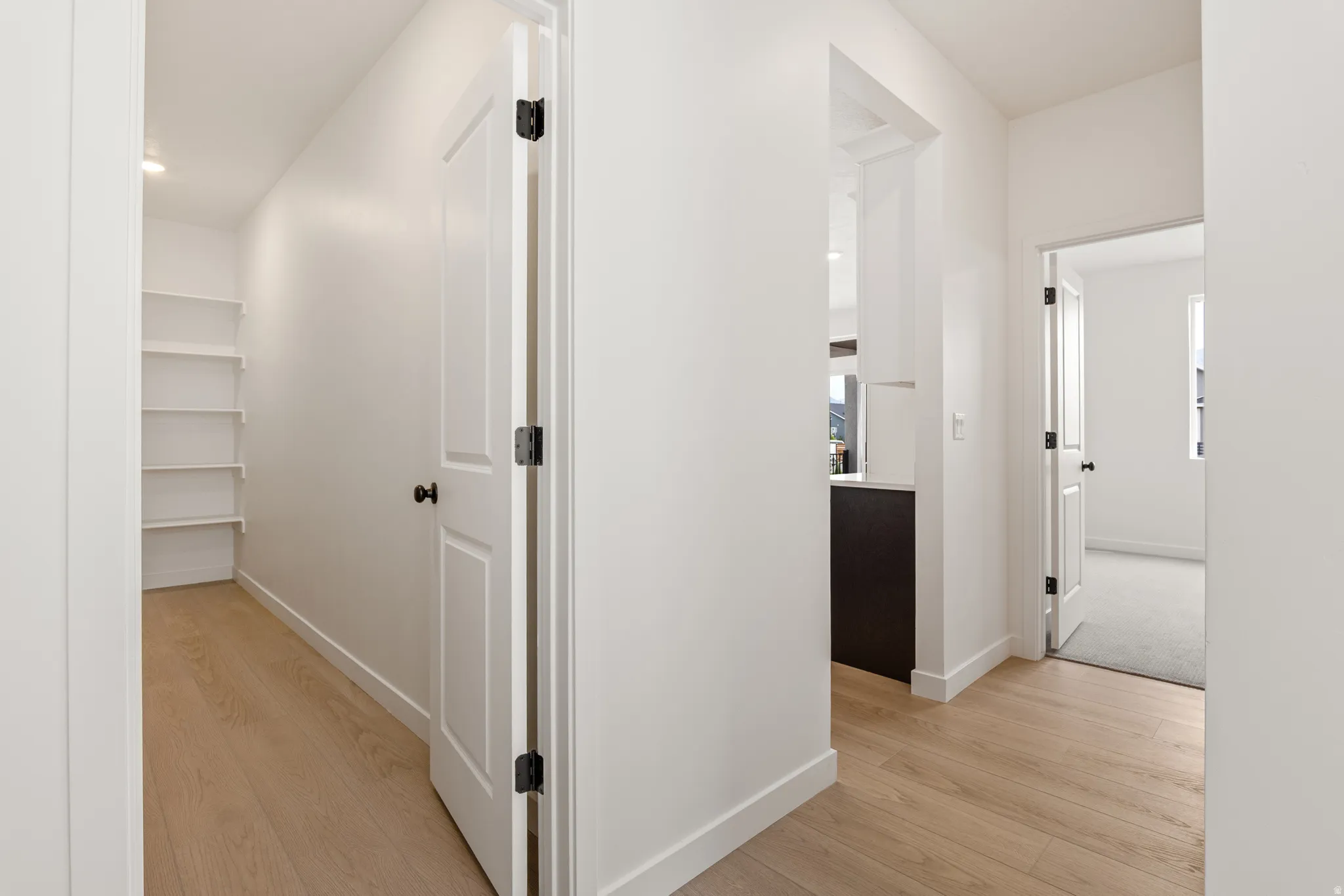 Hallway featuring wood-finish flooring, white walls, and white trim
