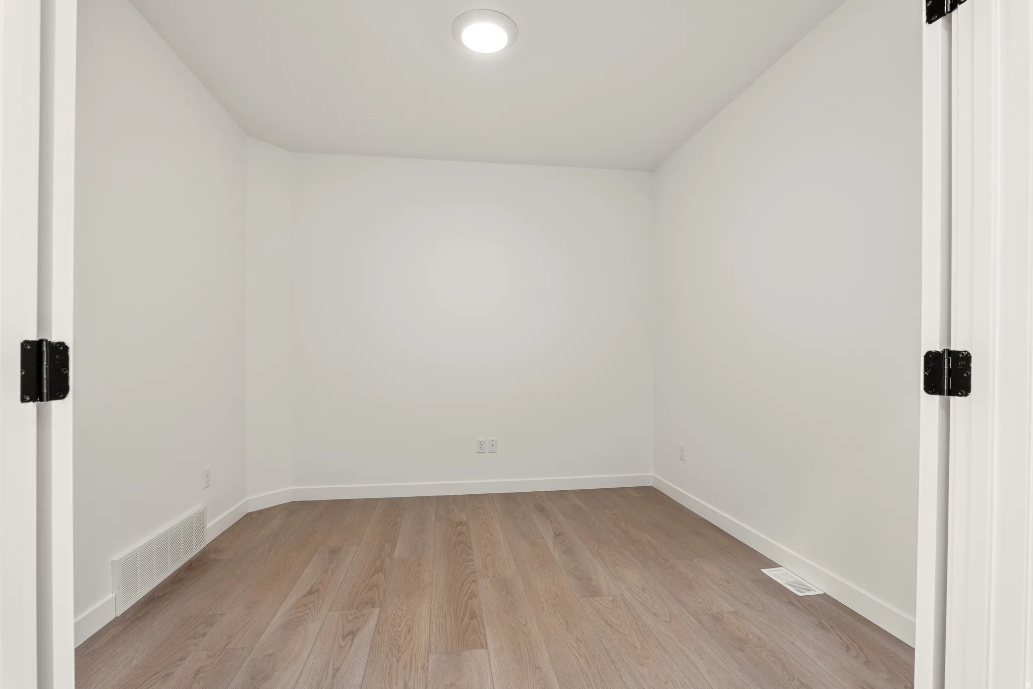 Room featuring light wood-finish flooring, white walls, and a ceiling-mounted light fixture