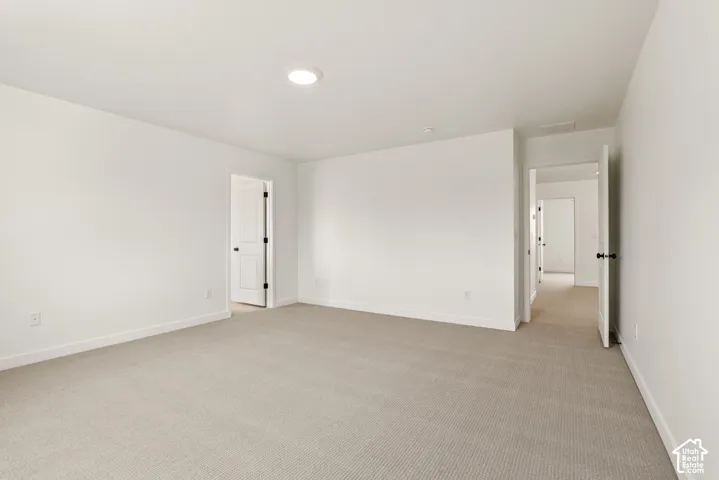 Expansive room featuring light-toned carpeting and crisp white walls