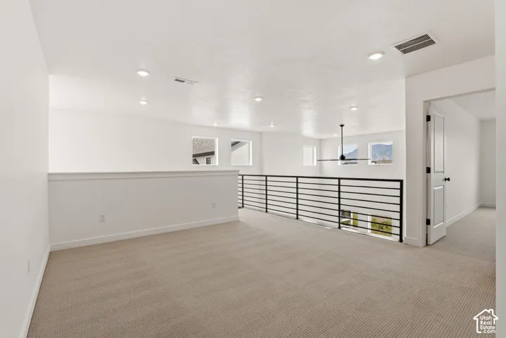 Open loft area featuring neutral carpeting, a modern black horizontal railing, recessed lighting, and a contemporary ceiling fan