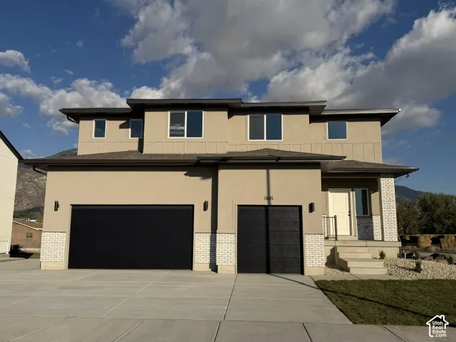 Two-story residence featuring a stucco exterior with brick accents, three-car garage with dark-finish doors, and concrete driveway