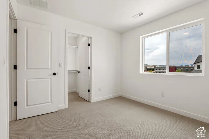 Carpeted room featuring a large window, white trim, and a closet with shelving