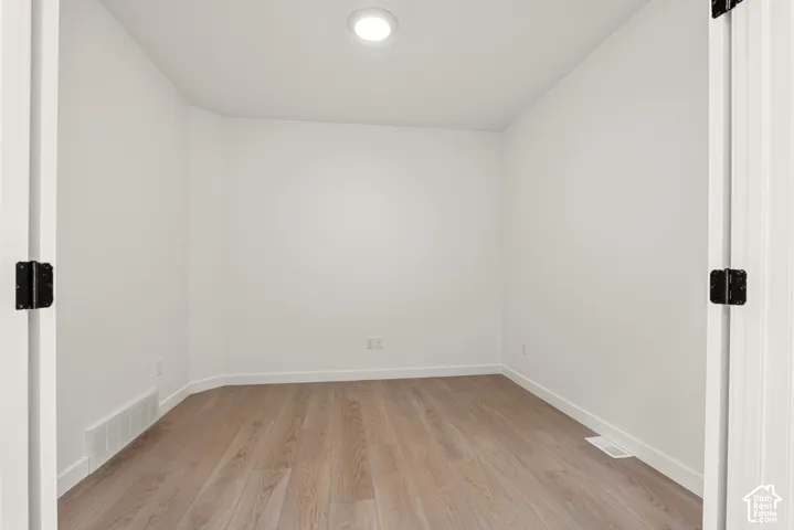 Room featuring light wood-finish flooring, white walls, and a ceiling-mounted light fixture