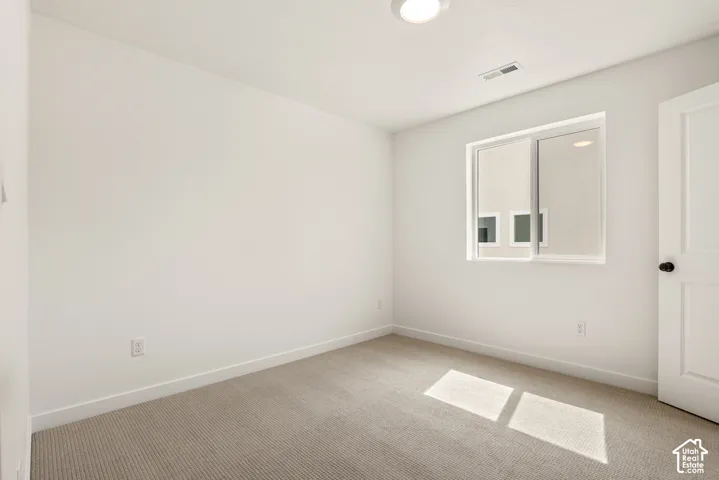 Carpeted room featuring a double-pane window, white trim, and a white interior door with a matte black knob