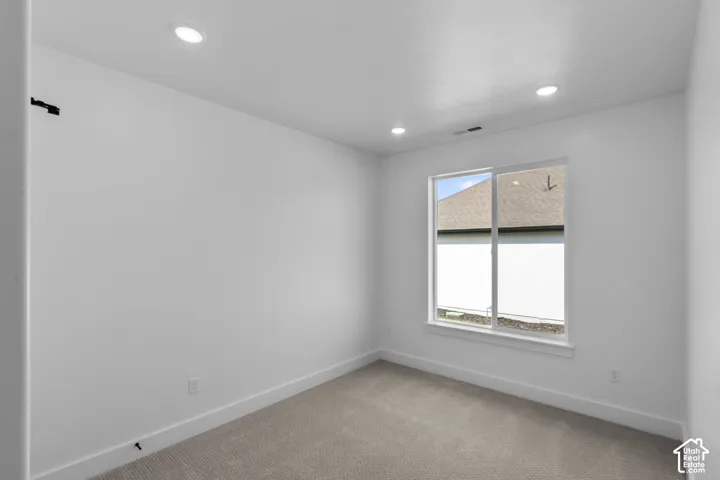 Neutral-toned carpeted room featuring a white single-pane window, white baseboards, and recessed ceiling lighting