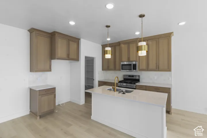 Modern kitchen featuring light wood-finish cabinetry and a central island with a built-in sink
