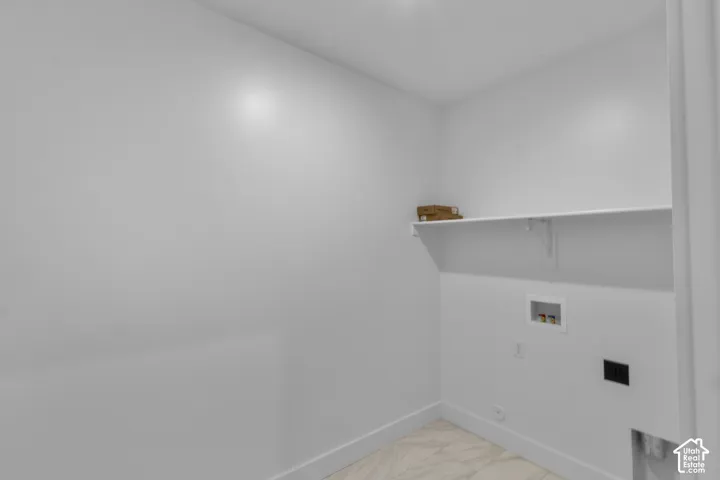 Utility space featuring a built-in white shelf, tile flooring, and white baseboards