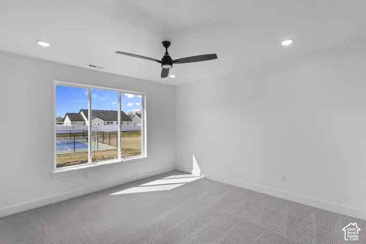 Room featuring a large triple-pane window, flush-mounted ceiling lights, a matte black ceiling fan, and light gray carpeting