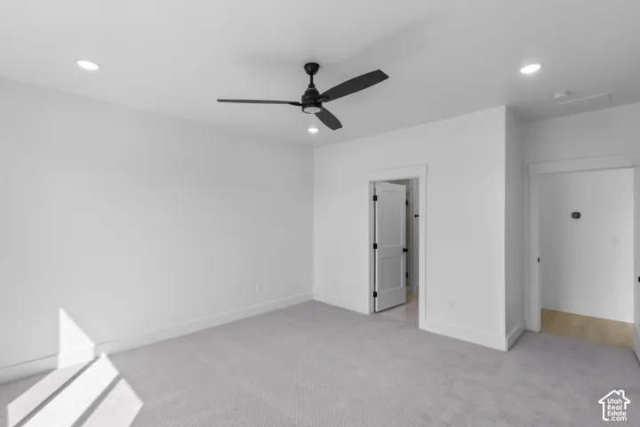 Room featuring light gray carpet flooring, white painted walls, and a black ceiling fan with integrated lighting